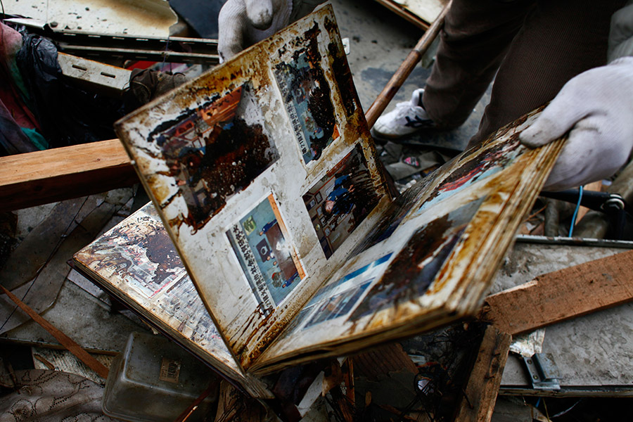 A local resident finds a family album belonging to his neighbor's under the debris where his house used to stand in Ofunato, Iwate.