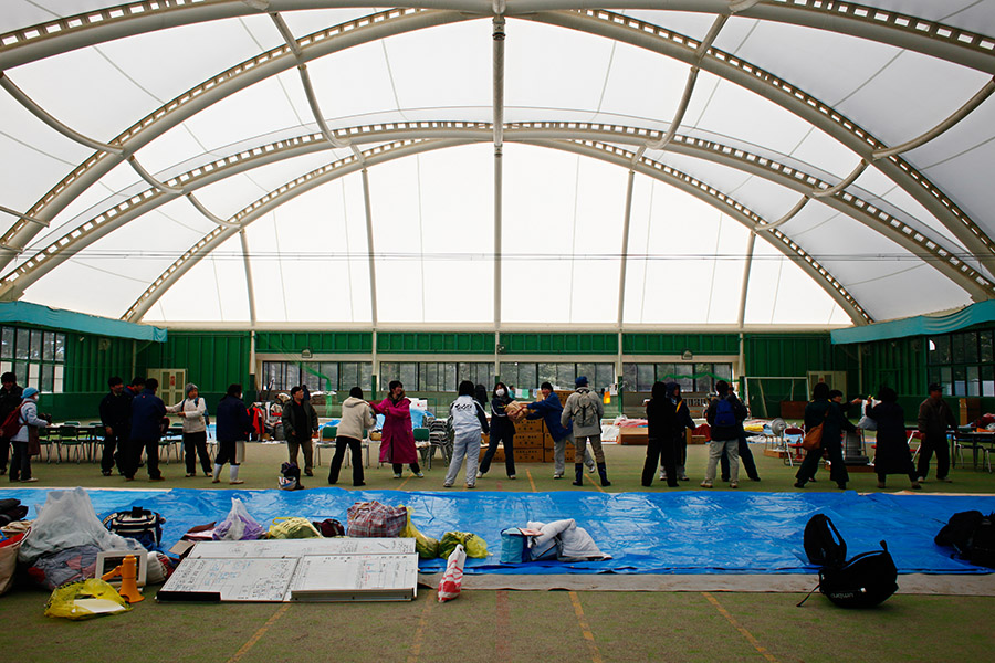 Evacuees line up to receive donated good at a shelter, originally an indoor sports facility in Rikuzentakata, Iwate, Japan.