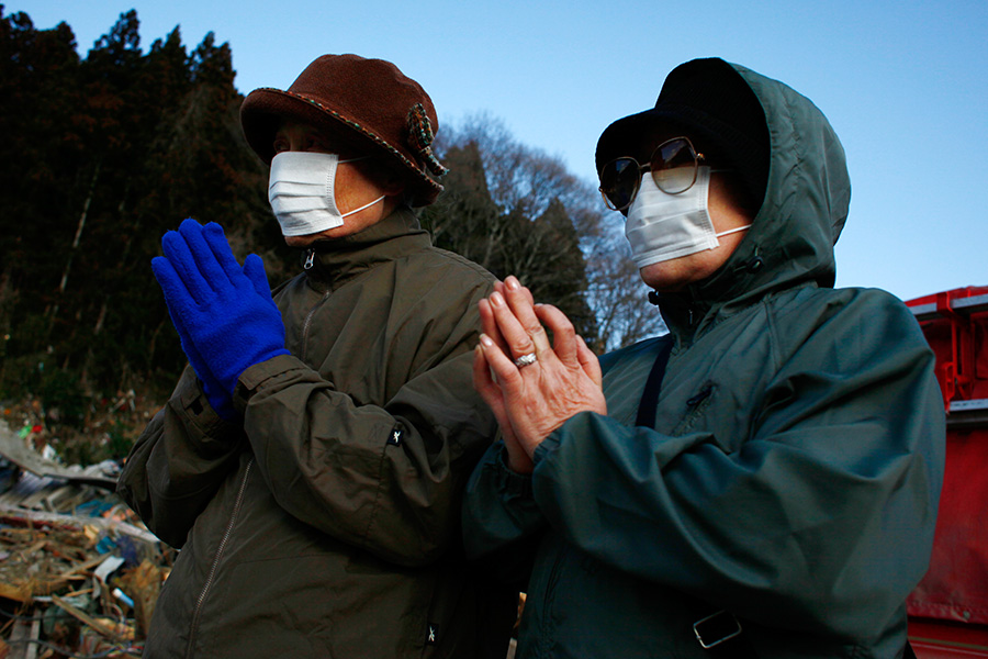 Women pray for the two found bodies in front of them amongst the rubbles in Rikuzentakata, Iwate, Japan.