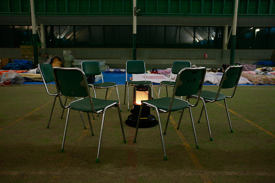 Empty chairs circle a heater at a shelter, originally an indoor sports facility where some evacuees stay in Rikuzentakata, Iwate, Japan.