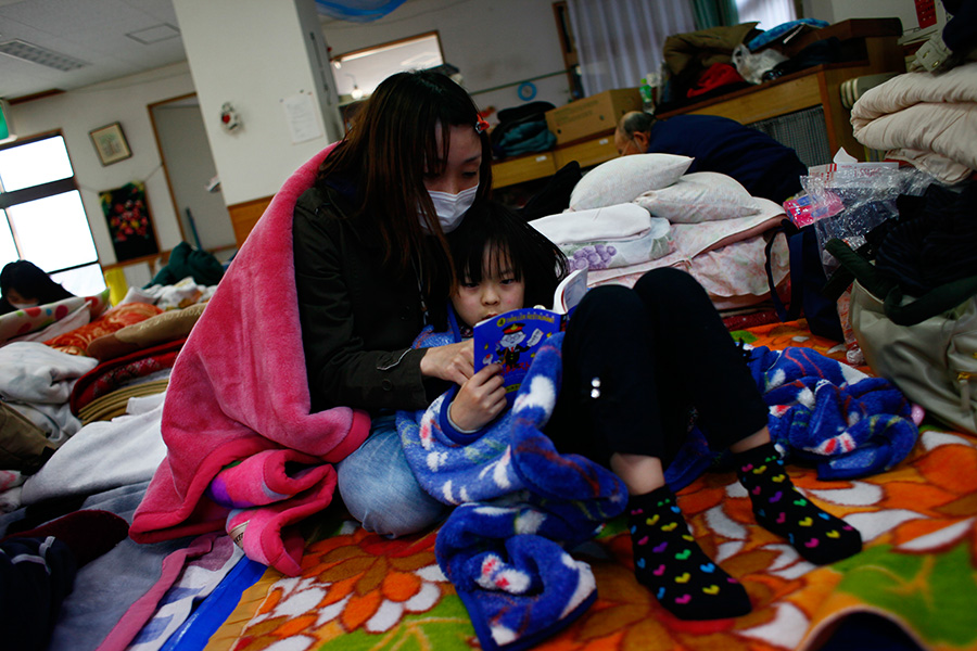 A mother and daughter read a book at a shelter in Rikuzentakata, Iwate, Japan.  
