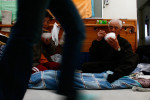 Elderly couple sit on their makeshift bed and eat their meal in the hallway of a retirement home, being used as a  shelter in Rikuzentakata, Iwate, Japan.  