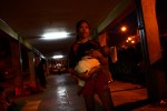 Mariana holds her 6-month-old daughter, Angela as the night falls at the underpass structure connecting the bus terminals. 