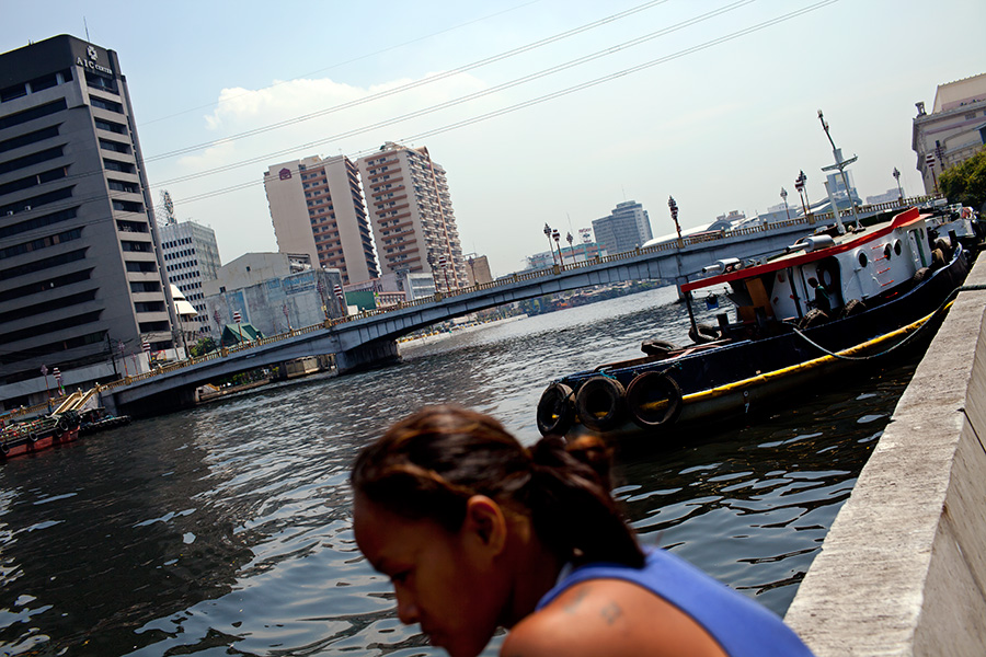 Veronica and others visit the Pasig river near where they live.  High-rise condominiums and office buildings line up along the river.