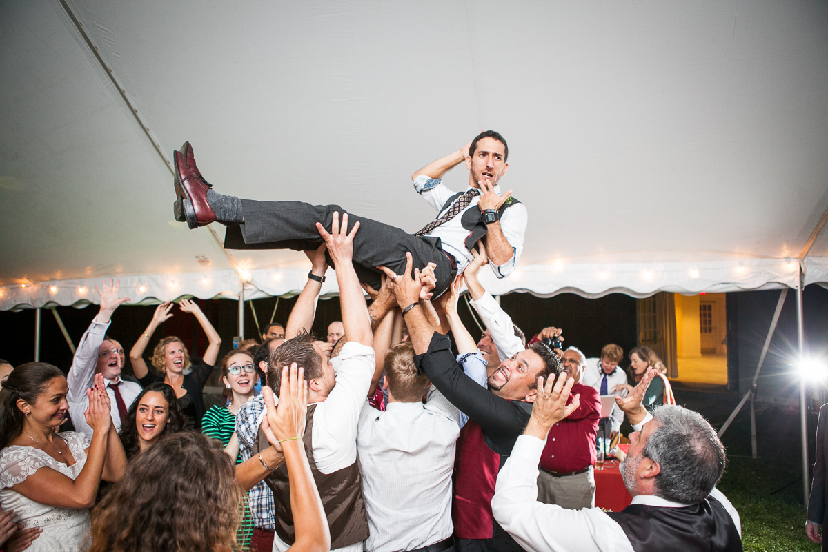 Brendan crowd surfs at his wedding reception at All Souls Interfaith Gathering in Shelburne, Vermont. by Vermont wedding photographers at Eve Event Photography