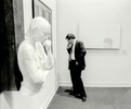 A visitor reads the artist’s information of a painting while mimicking a George Segal sculpture on the left at an exhibit at the Pennsylvania Academy of Fine Art in Philadelphia, PA.