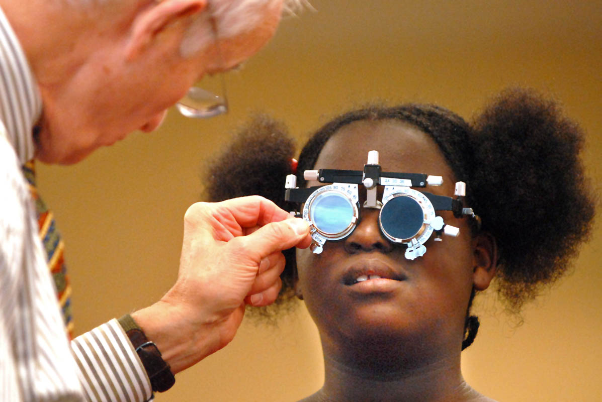 Optometrist Dr. Harry Mancoll changes a trial lens while giving an eye exam to a fourth grader at Benjamin Jepson Magnet School. ChildSight screens children's vision and gives them free glasses should they need them.  