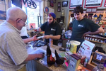 Brooklyn Farm & Pets employee Nate Gebo, center, makes change for customer Dick Booth, as two Serama chickens hang out on the counter. At right, is employee Mike Grady. 