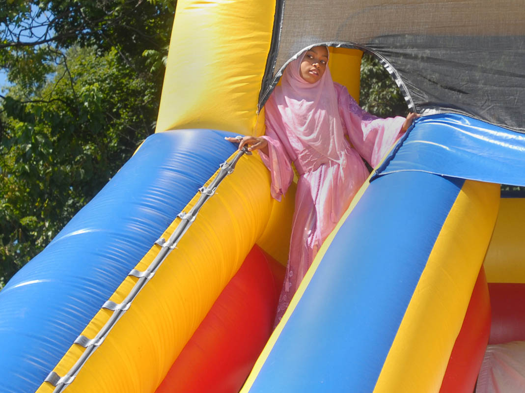 Bilqis Hashim, 12, looks down on others celebrating Eid ul-Fitr from her vantage point atop an inflatable slide behind Masjid Al-Islam.