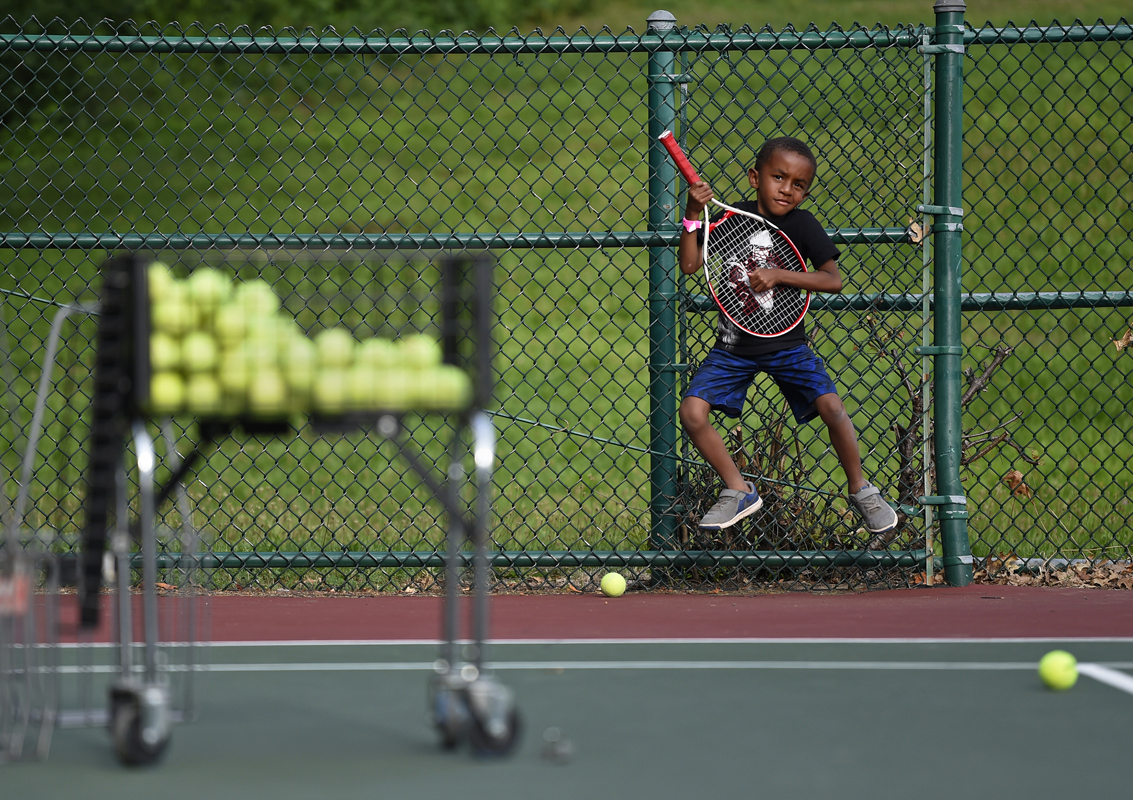 A boy pretends to play guitar with his tennis racquet at Phil Gordon Tennis Unlimited Summer Camp at Elizabeth Park.