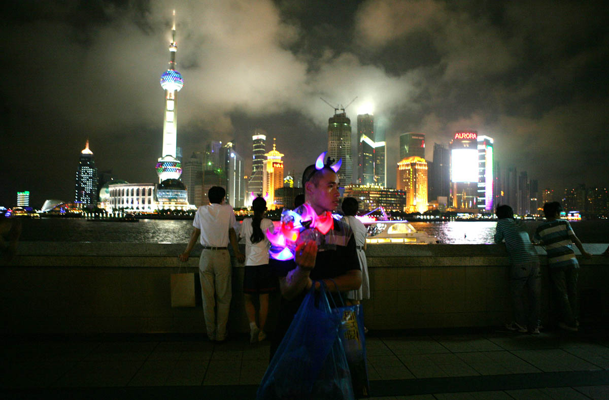 The Bund area, an elevated riverside promenade beside the Huangpu River, in Shanghai on September 15, 2008. In this photo a vendor hawks glow-in-the-dark devil horns while the Pudong business district can be seen across the river. The World Expo 2010 will be hosted by Shanghai with the theme  “Better City-Better Life” highlighting the city’s newfound status as a major economic and cultural hub.  