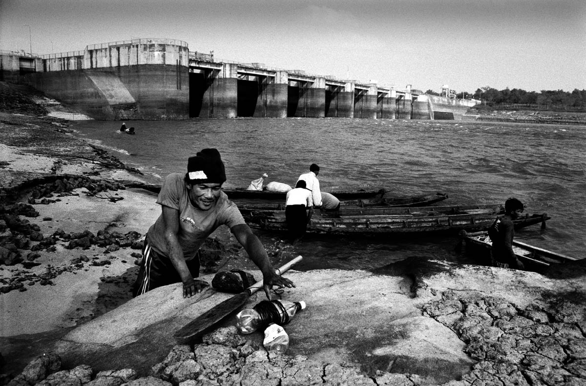Local fishermen waiting to go fishing in their boats on the day of the closing of the gates. For the next couple of days the area upriver from the dam gets filled with fish because the dam blocks their migration downstream to the Mekong.