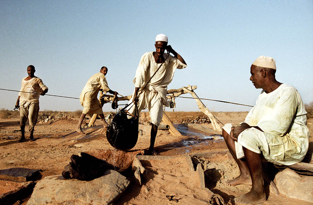 Nomads collecting water in a traditional way from a well in the desert.