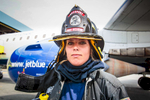 Boston, MA., July 24, 2013: Fire fighter Joanna Westland, 23, performs a drill on a Jet Blue jet as part of a training exercise. In some cases, fire fighters will board a plane if there is a report of smoke in the cabin and evacuate passengers via the portable stairs instead of the inflatable slides which can cause injuries. Boston has one of the best airline fighting fighting crews in the nation. Photograph by Evan McGlinn for The New York Times.