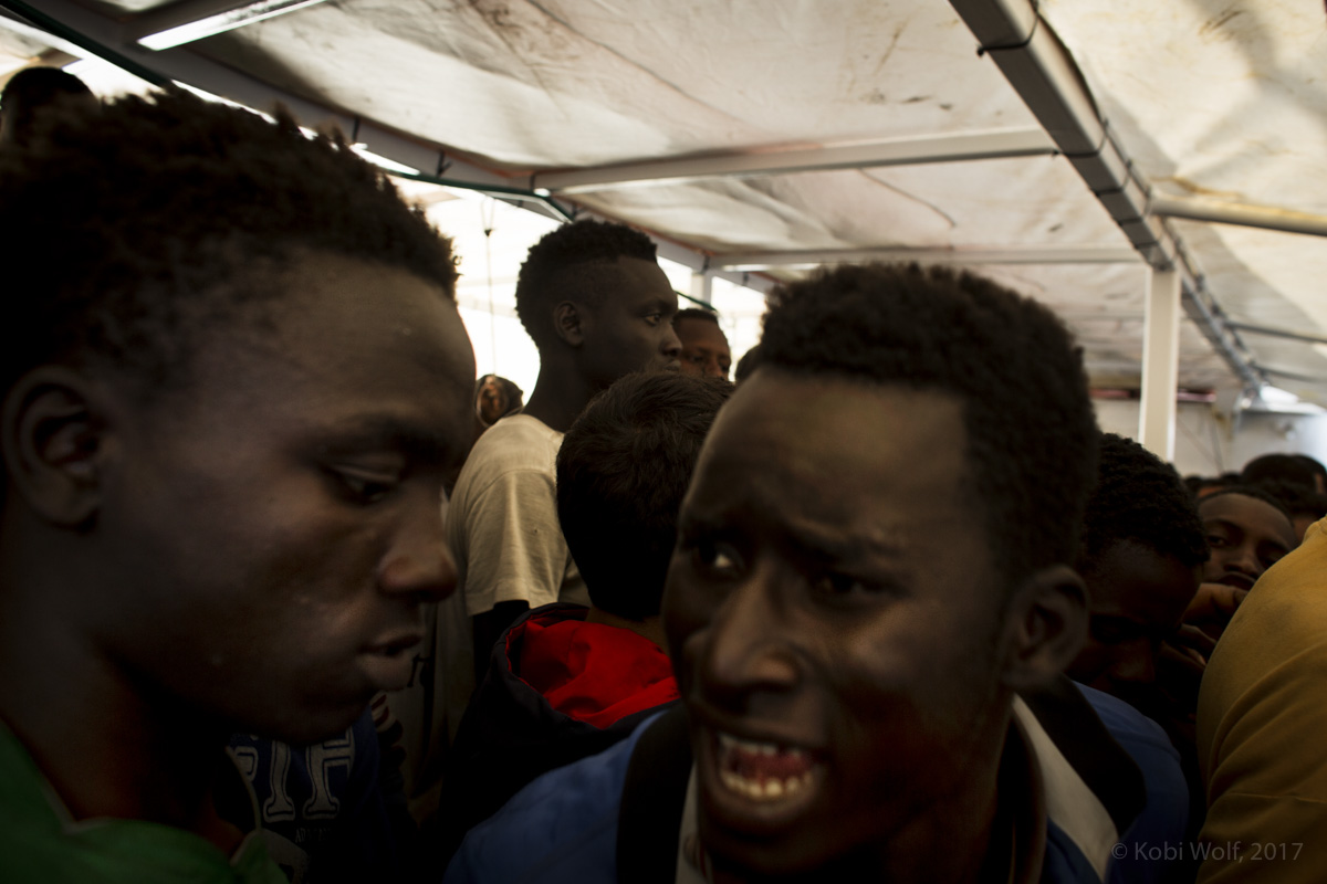 Africans Migrants Fighting for a bottle of water on the deck of the Procativa open arms ship  after being rescued in the central Mediterranean, in international waters off the Libyan coastal town of Sabratha. 
