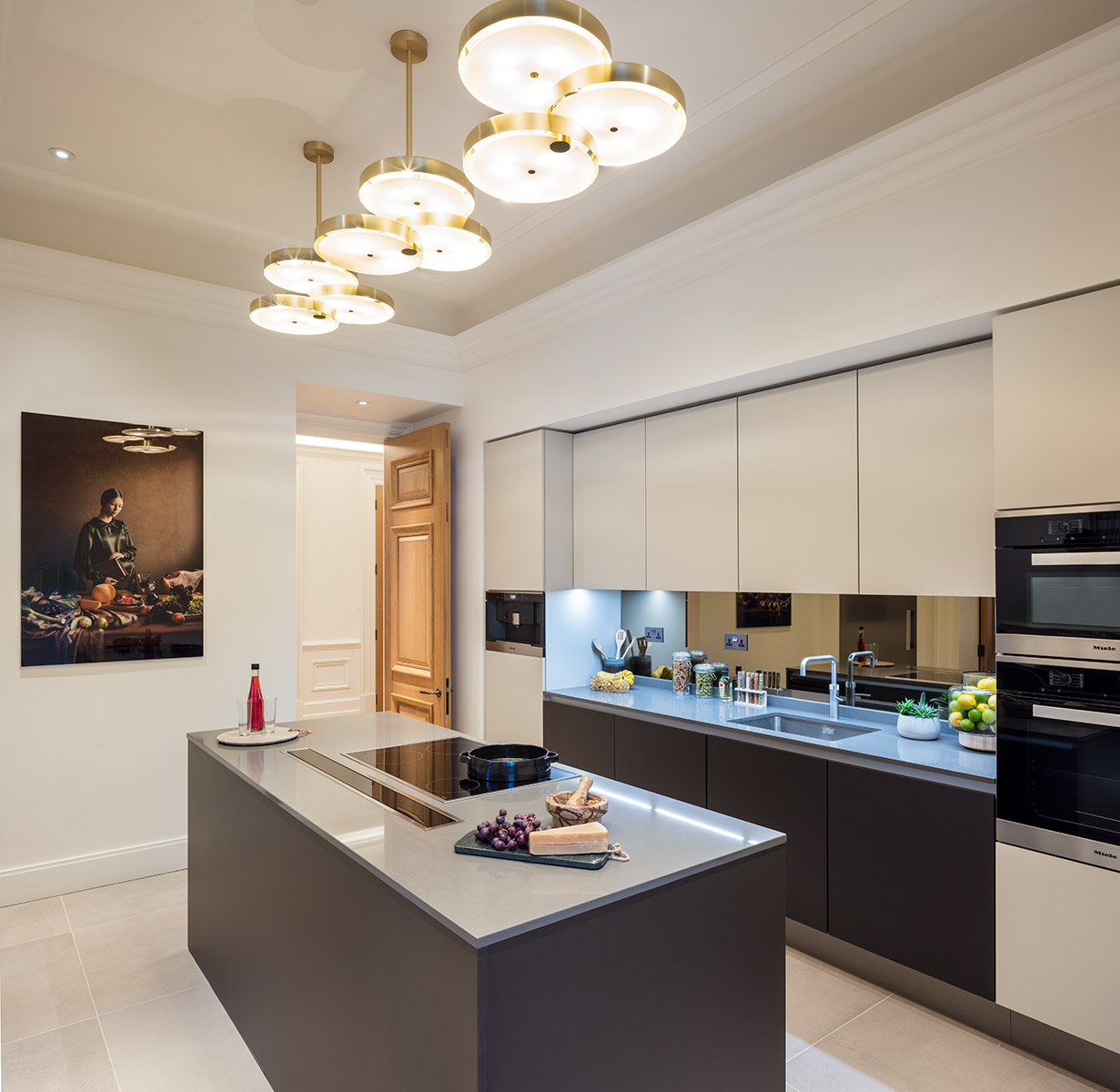 Photograph of a contemporary high end kitchen with island and classic artwork on wall. 
