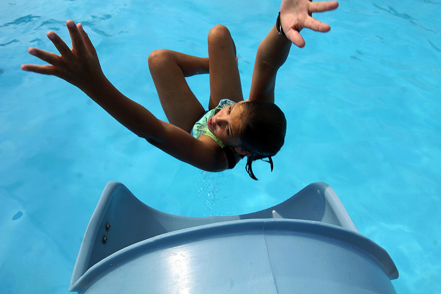  Eleven-year-old Kate Matthews shoots out of the water slide at the municipal pool on an 80-degree summer day. (Reena Rose Sibayan | The Clark Eagle)