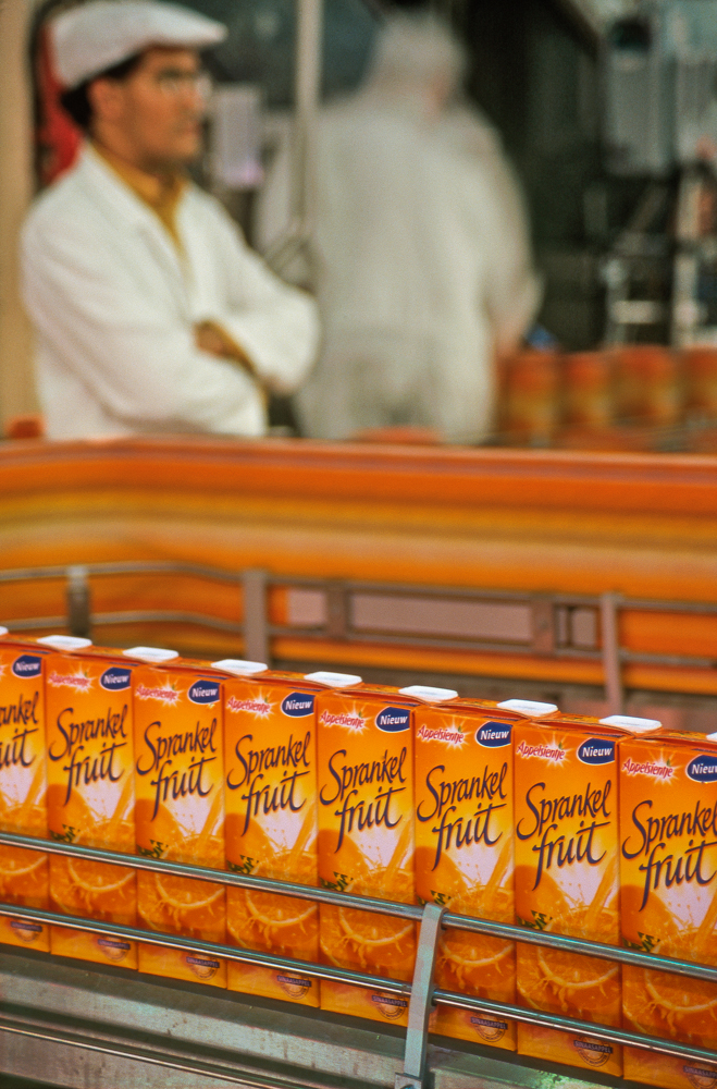 Fruit juice packaging line, BelgiumA supervisor watches over an orange juice packaging line at a fruit juice processing plant in Belgium.