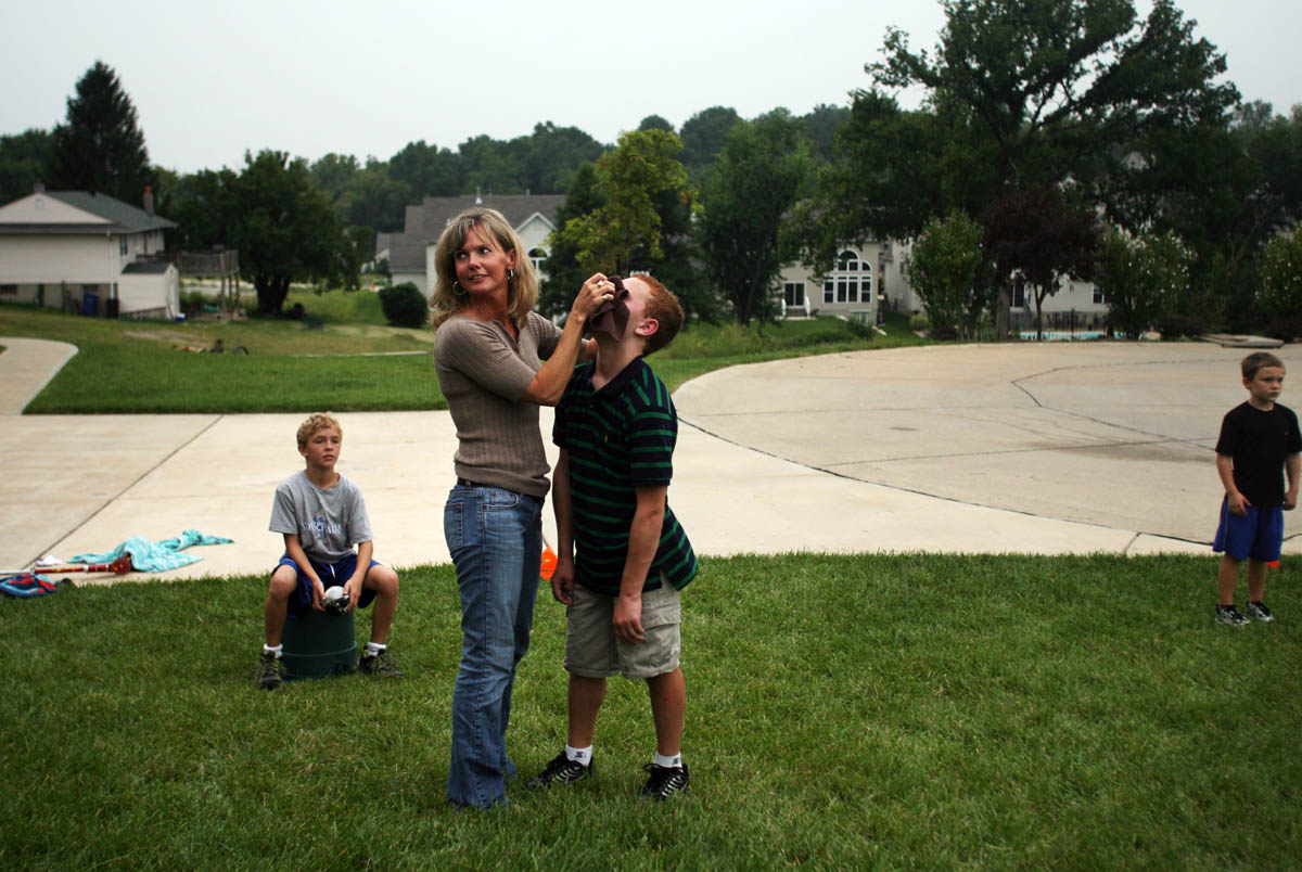 Krista holds Brendan's nose after it starts to bleed while playing a game of touch football in the front yard. 
