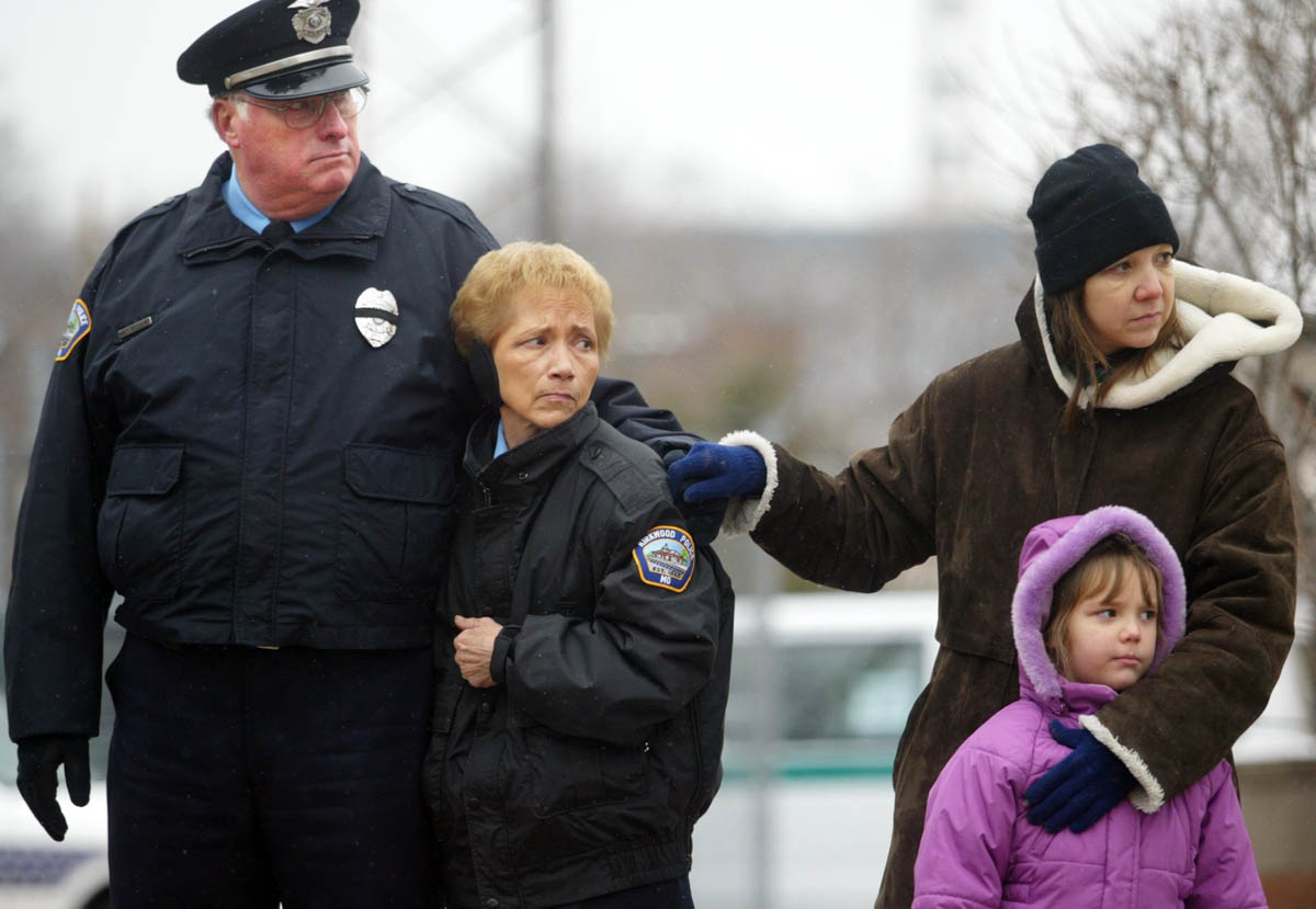 Left, Kirkwood police officer Dave Docter, Kirkwood police court clerk Kathy Hatcher, Kirkwood residents Kimberly Garritson and her daughter Anna Wells, 6, watch as Kirkwood Police Officer Thomas Ballman's funeral procession passed the Kirkwood police station.