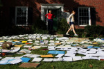 Yvonne Pierce walks out of her house as Kathryn Pierce stands and looks at the hundreds of documents spread across the lawn at Yvonne's home on Haddington Court in Clayton. The front lawn was covered in hundreds of wet family documents that were recovered from the flooded basement and layed out to dry.  Pierce said their street flooded Sunday morning when the sewer backed up during the storm.