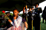 Maya Mercer, left, holds a rose as Newport News police officers wait to place the Flag, Boots and Hat during Thursday's candlelight memorial service to remember the 11 police officers who have died on duty and to honor those who serve today.