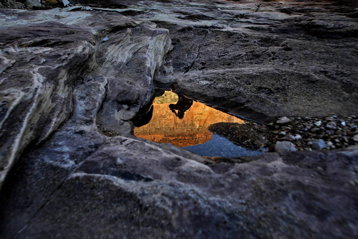 Tess McEnroe of Minneapolis, Minn. is reflected in a puddle of water as she stops during a hike through the Grand Canyon to shield her eyes from the sun and admire the view. McEnroe and eleven others spent over two weeks whitewater rafting down the Colorado River through the Grand Canyon.