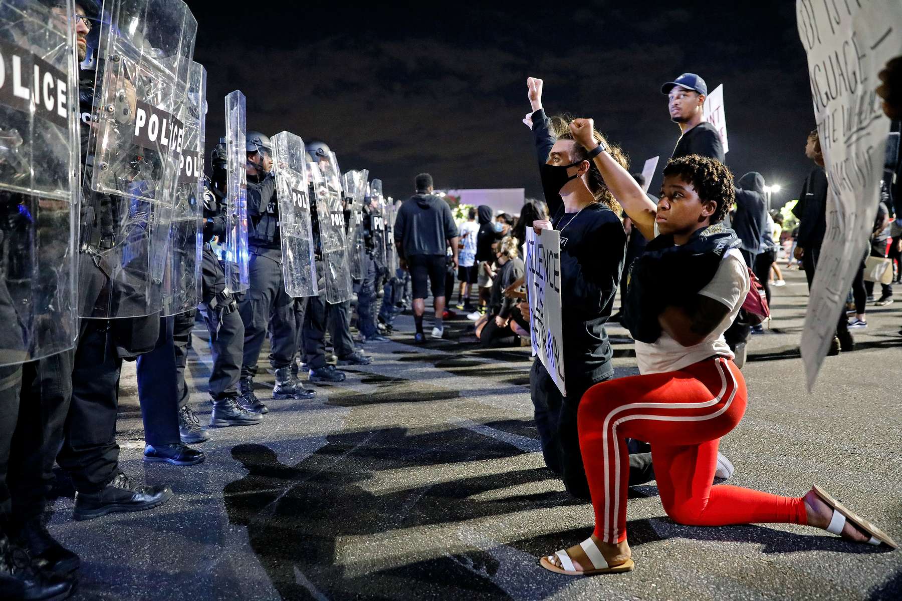 A protester kneels before Hampton police officers at Peninsula Town Center in Hampton Tuesday evening June 2, 2020. 