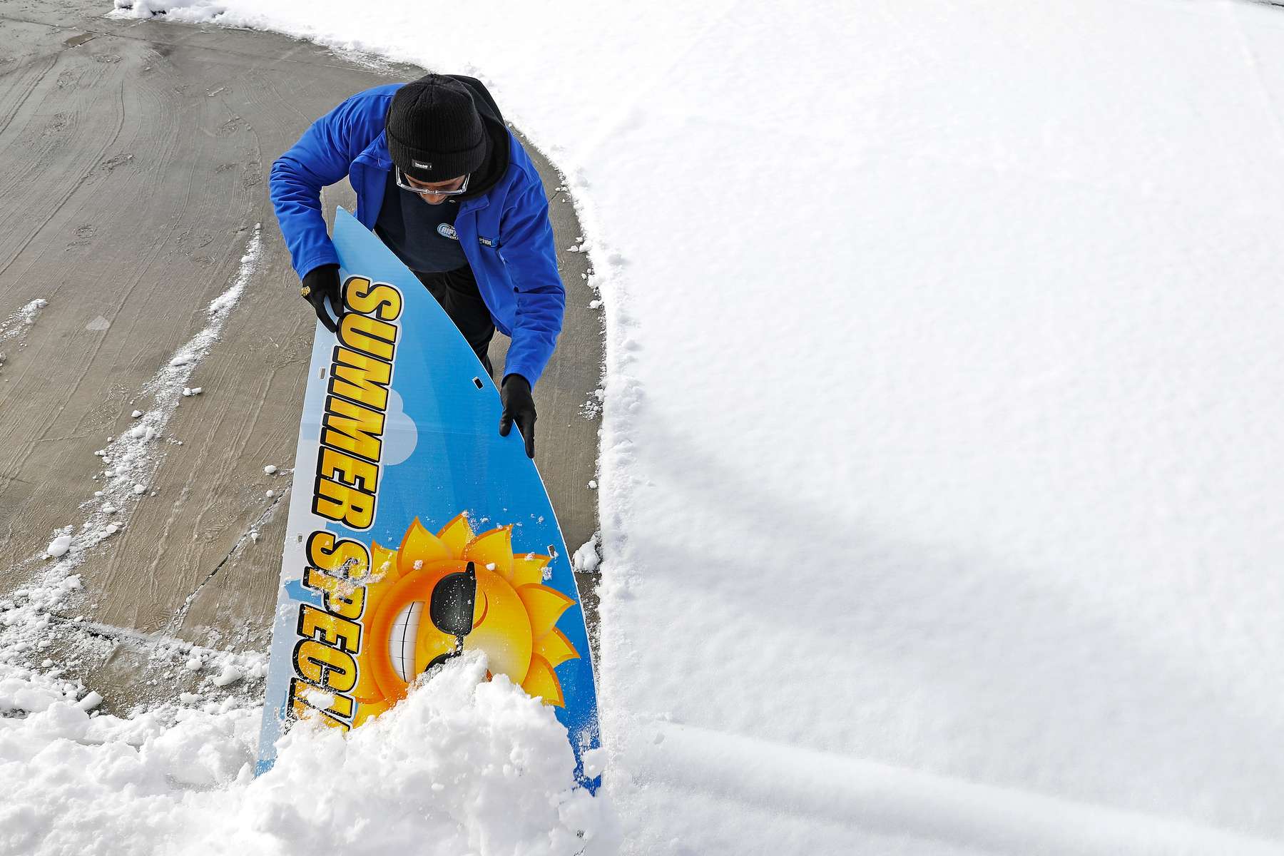 Keith Graves uses a sign as a shovel to clear snow from the lot of the RipTide Car Wash in Hampton Saturday morning January 22, 2022. 