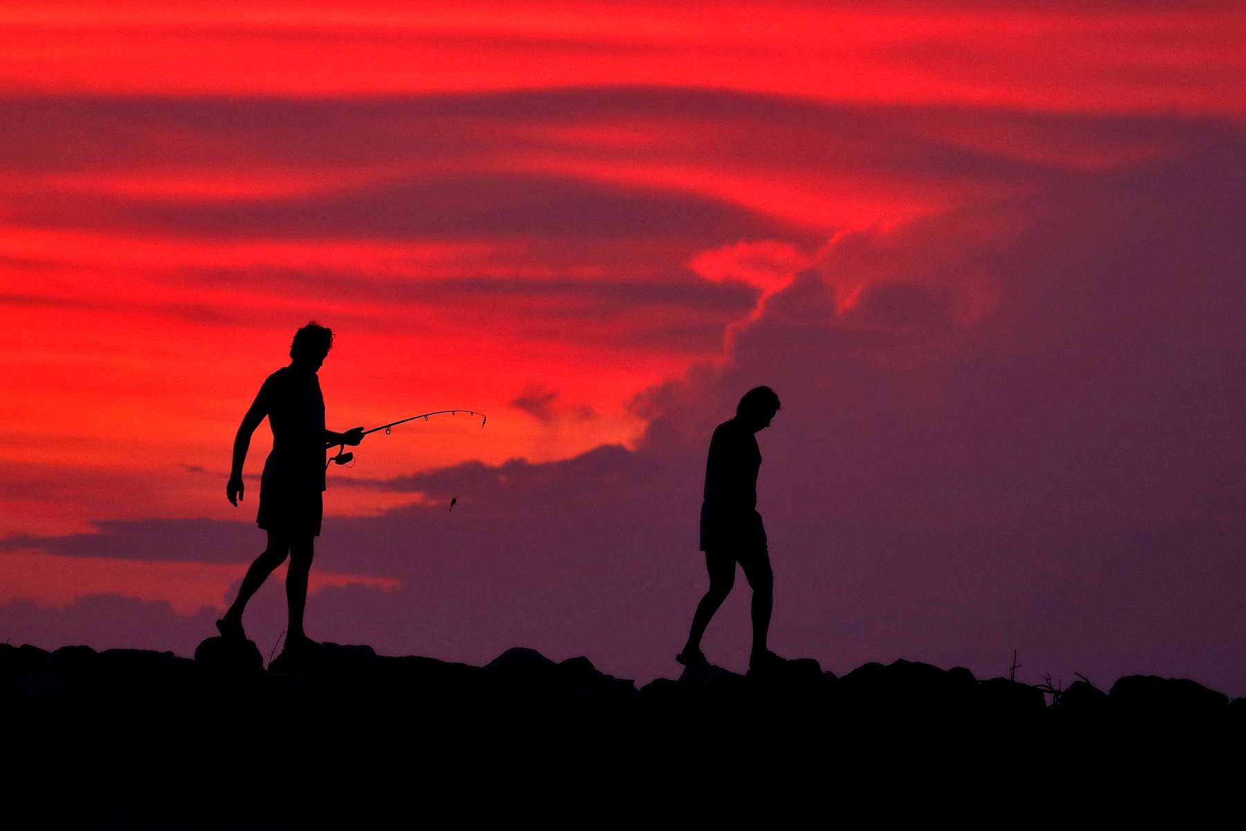 A couple navigates the rocks while fishing at Huntington Beach after sunset in Newport News Wednesday evening August 21, 2019. 