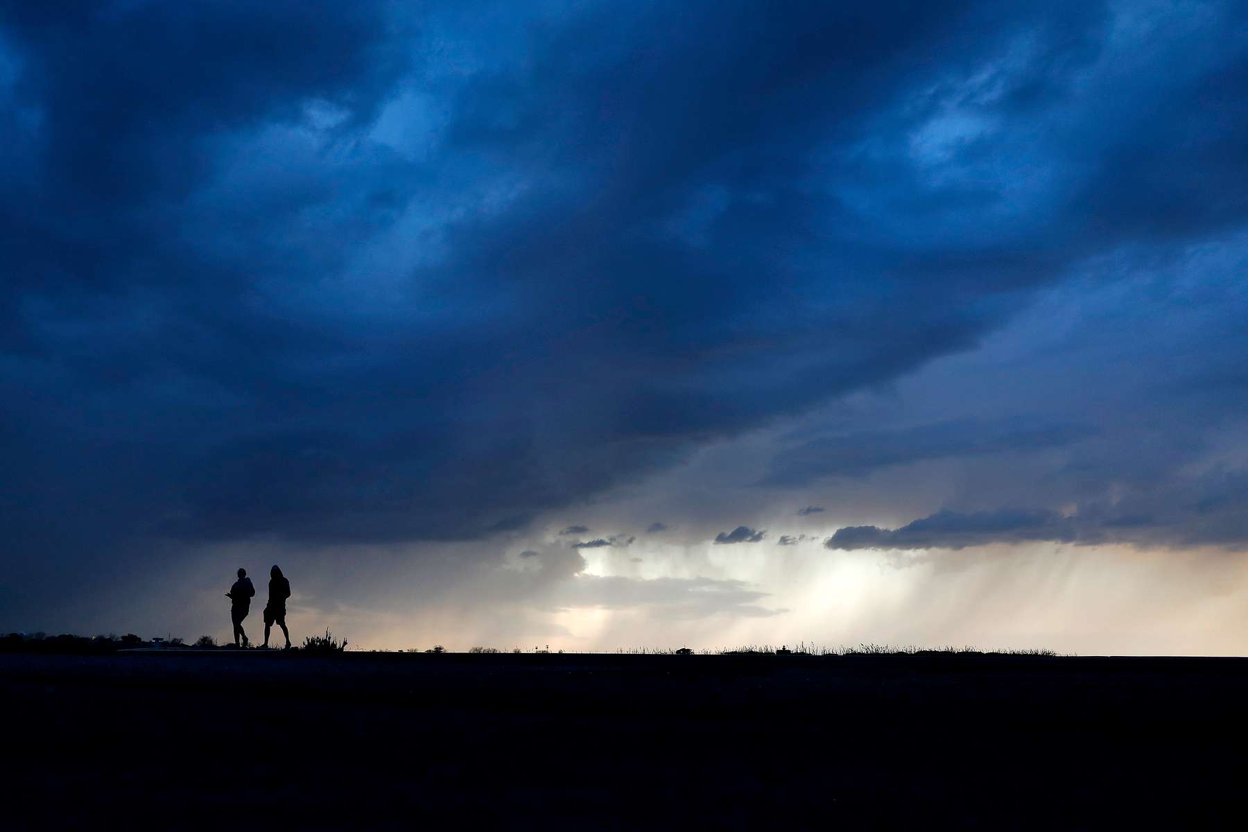 Storm clouds roll over Ft. Monroe as people walk along Stilwell Drive Tuesday evening April 7, 2020. 