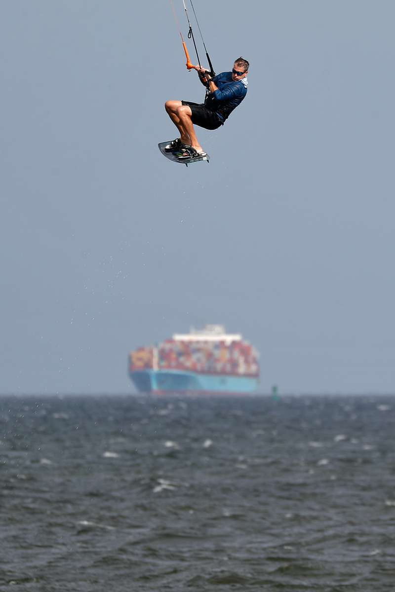 A kite surfer flies through the air as a container ship passes in the background Wednesday afternoon September 1, 2021. 