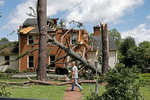 A man walks past a damaged house with a chainsaw in the Riverview neighborhood of Suffolk after Tropical Storm Isaias moved through the region Tuesday August 4, 2020.