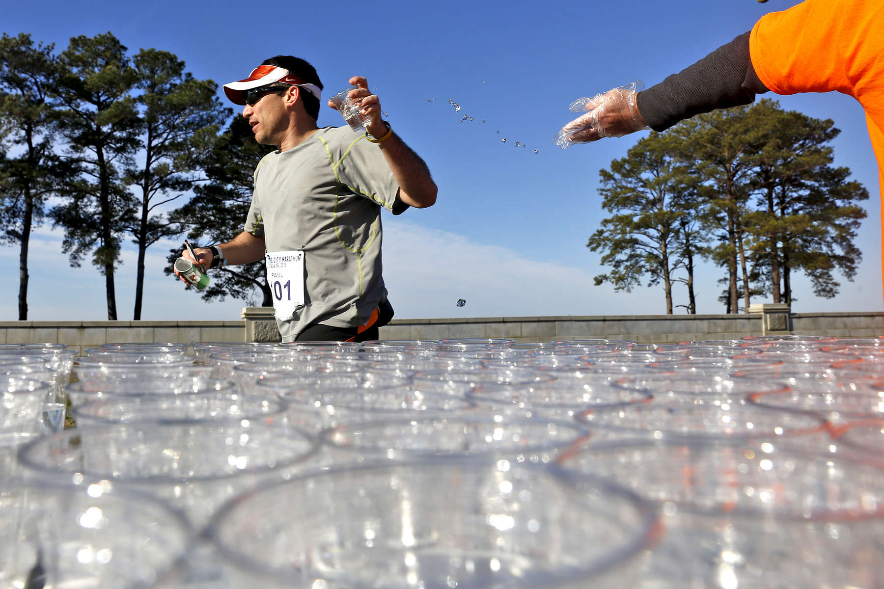 A runner grabs a glass of water from a volunteer at the Lions Bridge during the One City Marathon in Newport News Sunday morning. 