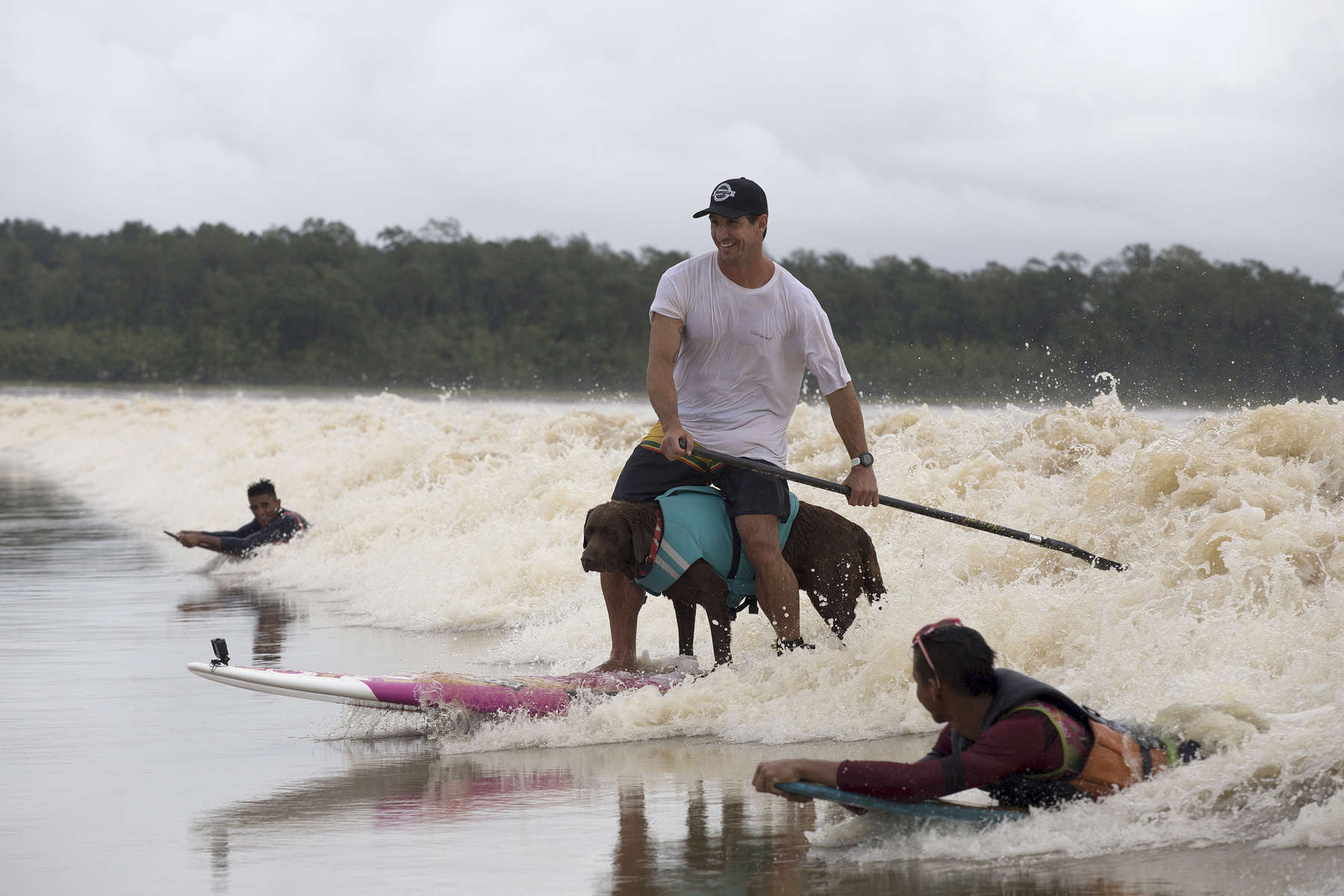 Ivan Moreira and Bono surf the tidal bore wave in between locals Valdinei Farias Mendes and Ruan Maciel Borges. Bono often likes to ride the board this way.