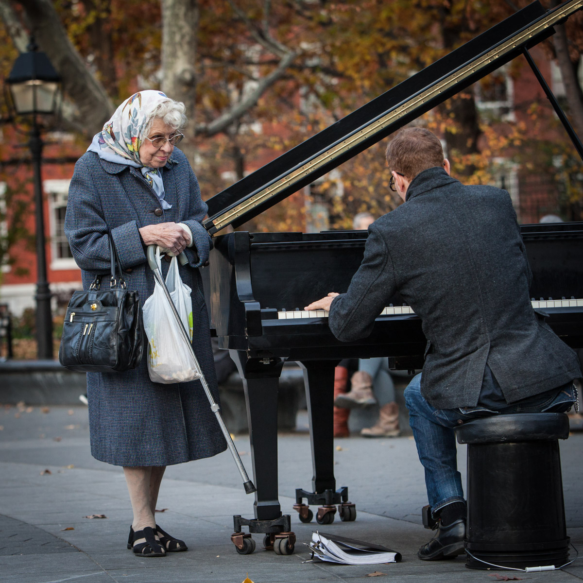 A woman listens to Colin Huggins play the piano in Washington Square Park in Greenwich Village, NY. 