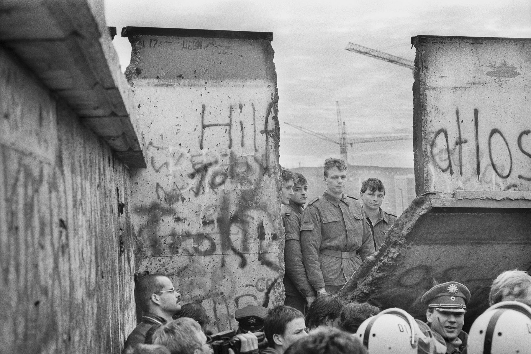 East German soldiers appear behind a piece of the wall torn down by the crowd next to the Brandenburg Gate on November 11, 1989