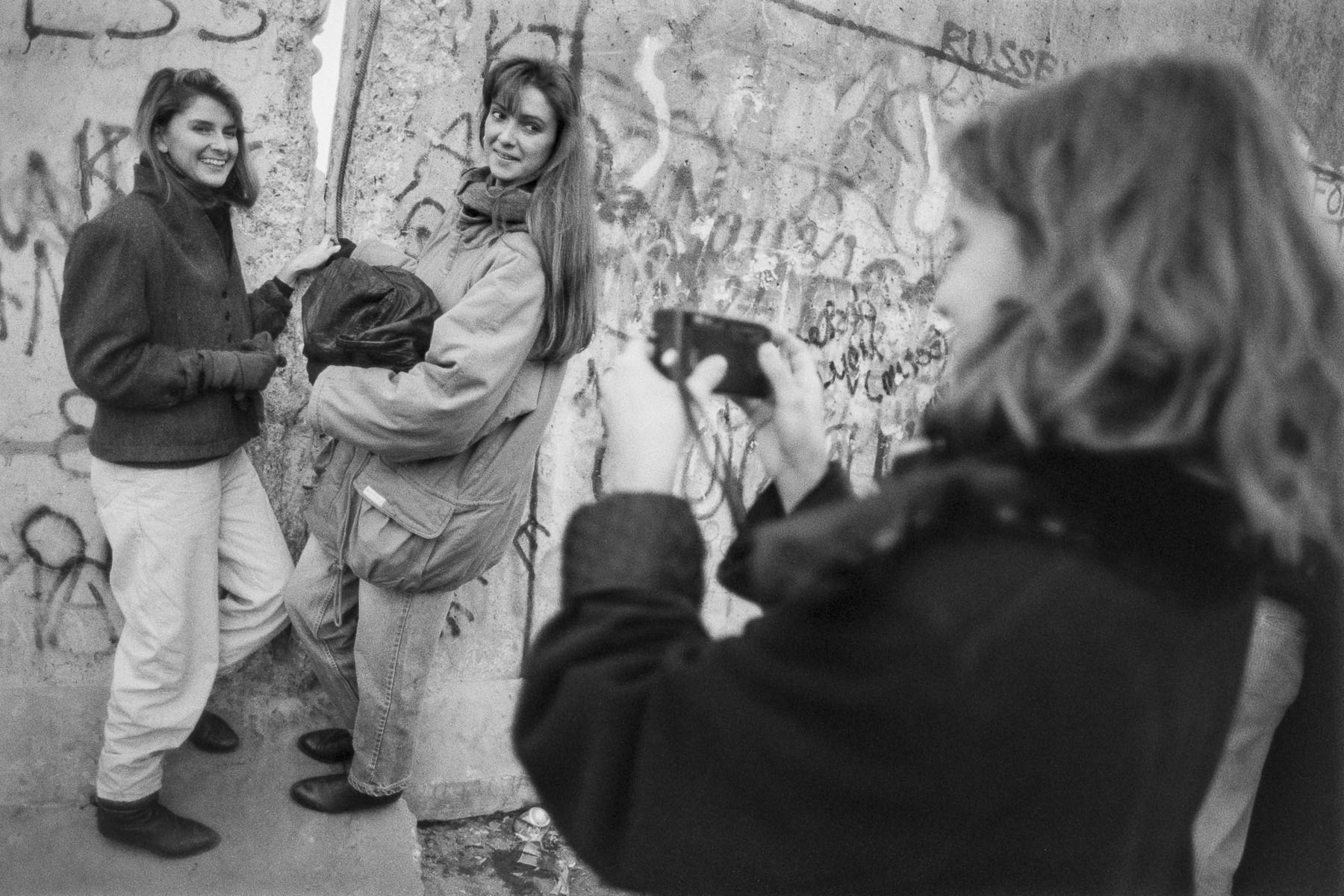 West Berliner women pose for photos in front of a gap in the Berlin Wall on November 11, 1989