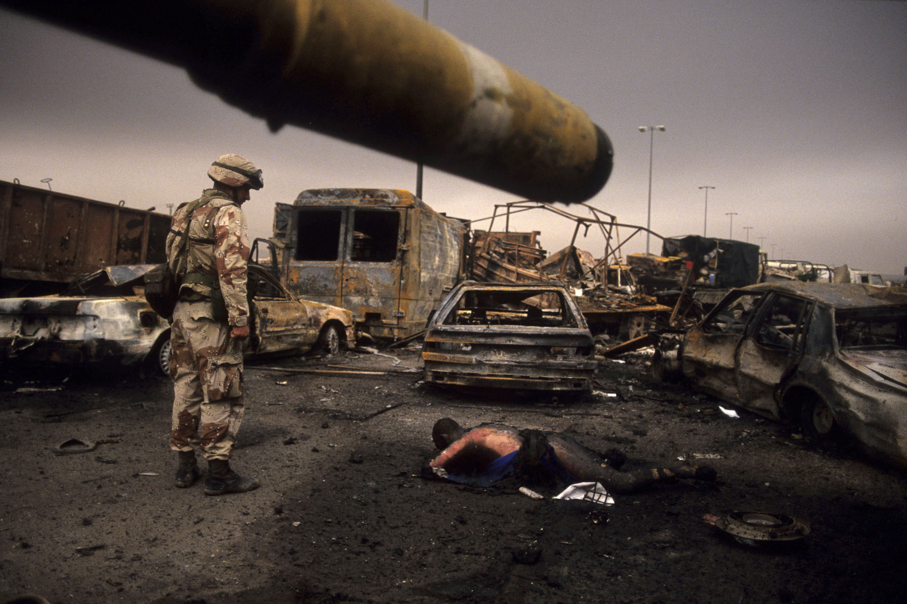 A U.S. trooper looking at an Iraqi soldier’s corpse in February 1991