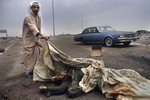 A Kuwaiti man showing an Iraqi soldier’s corpse on the road to Basra in February 1991