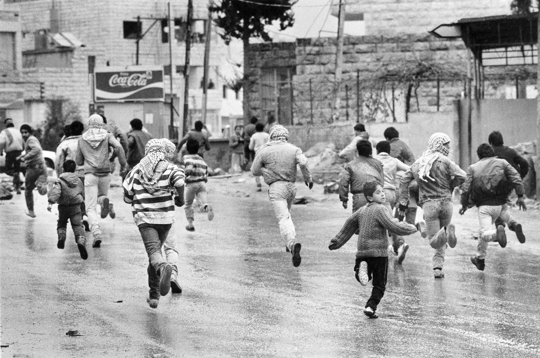 Young Palestinians running away from Israelian soldiers during a demonstration in January 1988