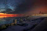 The sun started to break over the horizon as the city skyline glowed with artifical light in the early morning hours of the Polar Vortex at the Fullerton Street Beach along the frozen shore of Lake Michigan in Chicago. 