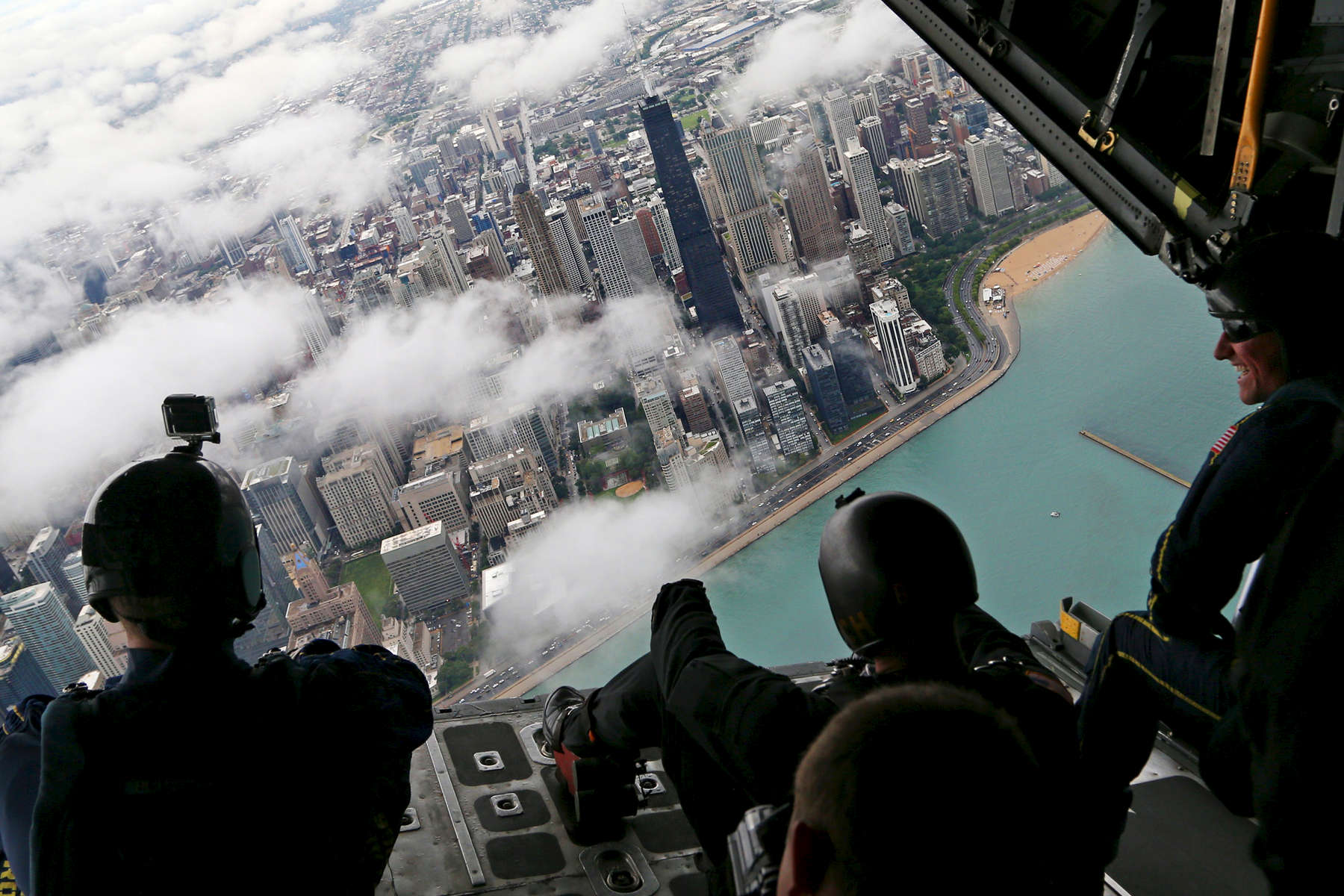 Members of the Navy's Leap Frogs and Army's Golden Knights parachute teams took in the view from the back of a C130h airplane as it flew over the John Hancock Center en route to the annual Air and Water Show in Chicago. 