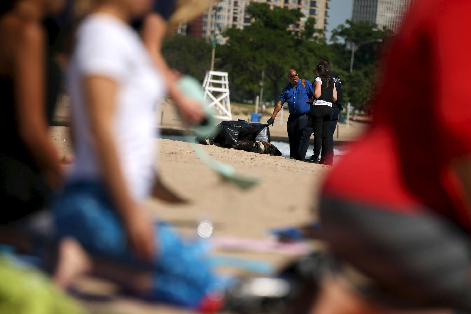 Participants of a morning beach yoga class practiced their poses as police investigated the scene nearby where a body was discovered at North Avenue Beach in Chicago.