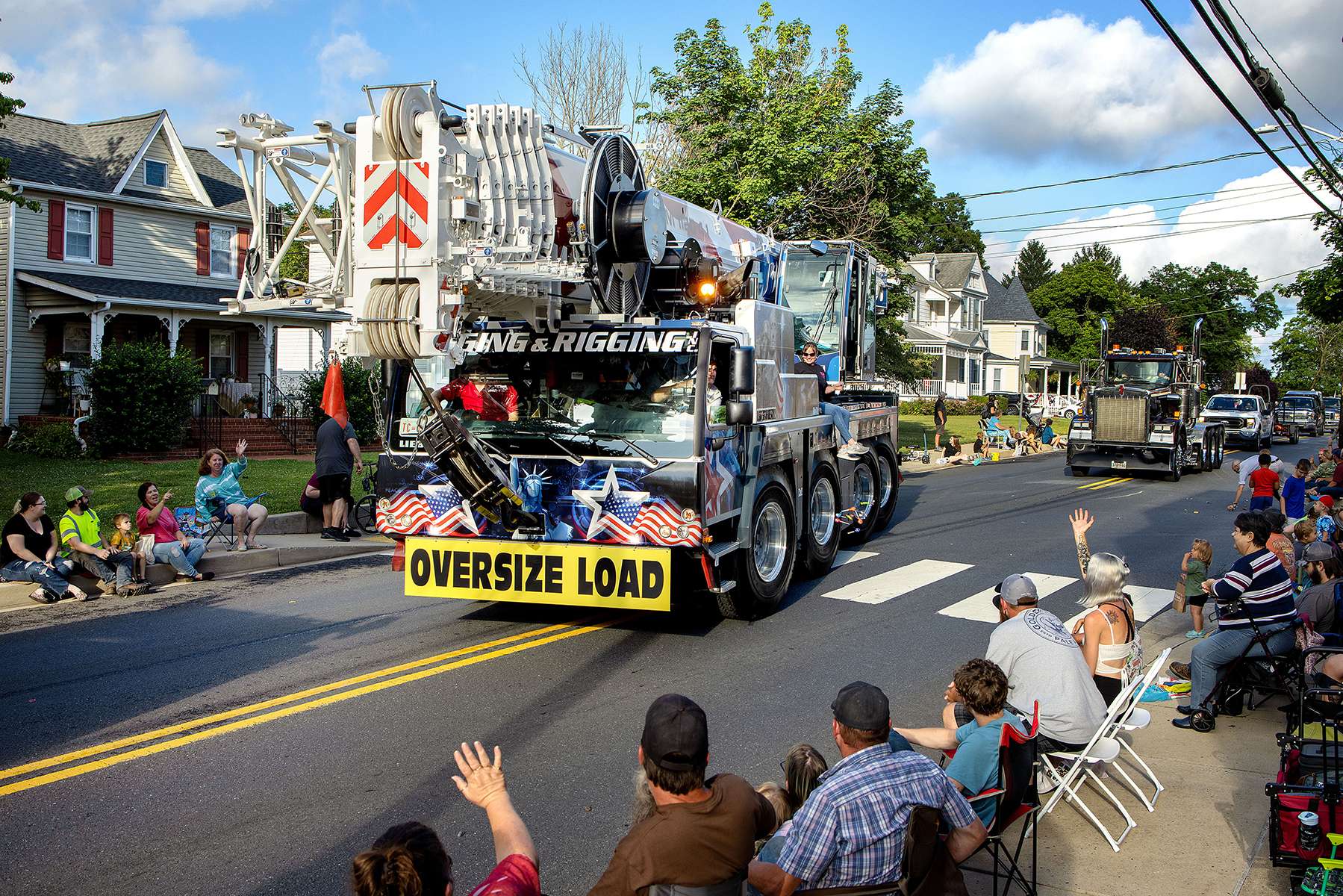 A rigging truck from a local company is driven through town, with employees tossing out candy to children along the way, during the parade for the annual Thurmont Fireman’s Carnival in Thurmont, Maryland on June 23, 2022. Fireman’s carnivals are a feature of the summer social calendar in many rural communities across the country that depend on a volunteer fire fighting force. The carnivals are often the main fundraiser for these departments, allowing them to buy fire trucks and other equipment. ⁠