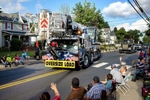 A rigging truck from a local company is driven through town, with employees tossing out candy to children along the way, during the parade for the annual Thurmont Fireman’s Carnival in Thurmont, Maryland on June 23, 2022. Fireman’s carnivals are a feature of the summer social calendar in many rural communities across the country that depend on a volunteer fire fighting force. The carnivals are often the main fundraiser for these departments, allowing them to buy fire trucks and other equipment. ⁠