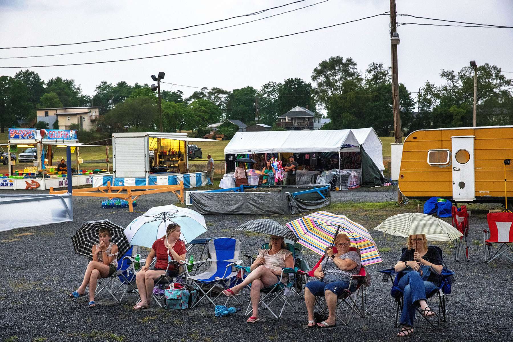 Audience members for the 2021 Little Miss Newville pageant wait out a rainstorm during the 61st Annual Newville Community Fair at the Newville Fairgrounds in Newville, Pennsylvania on July 7, 2021. A fundraiser hosted every year by the Newville Lions Club, the fair charges no admission or parking fees, generating funds from on-site sales and donations from participants. During the year, these funds help support local organizations and events.