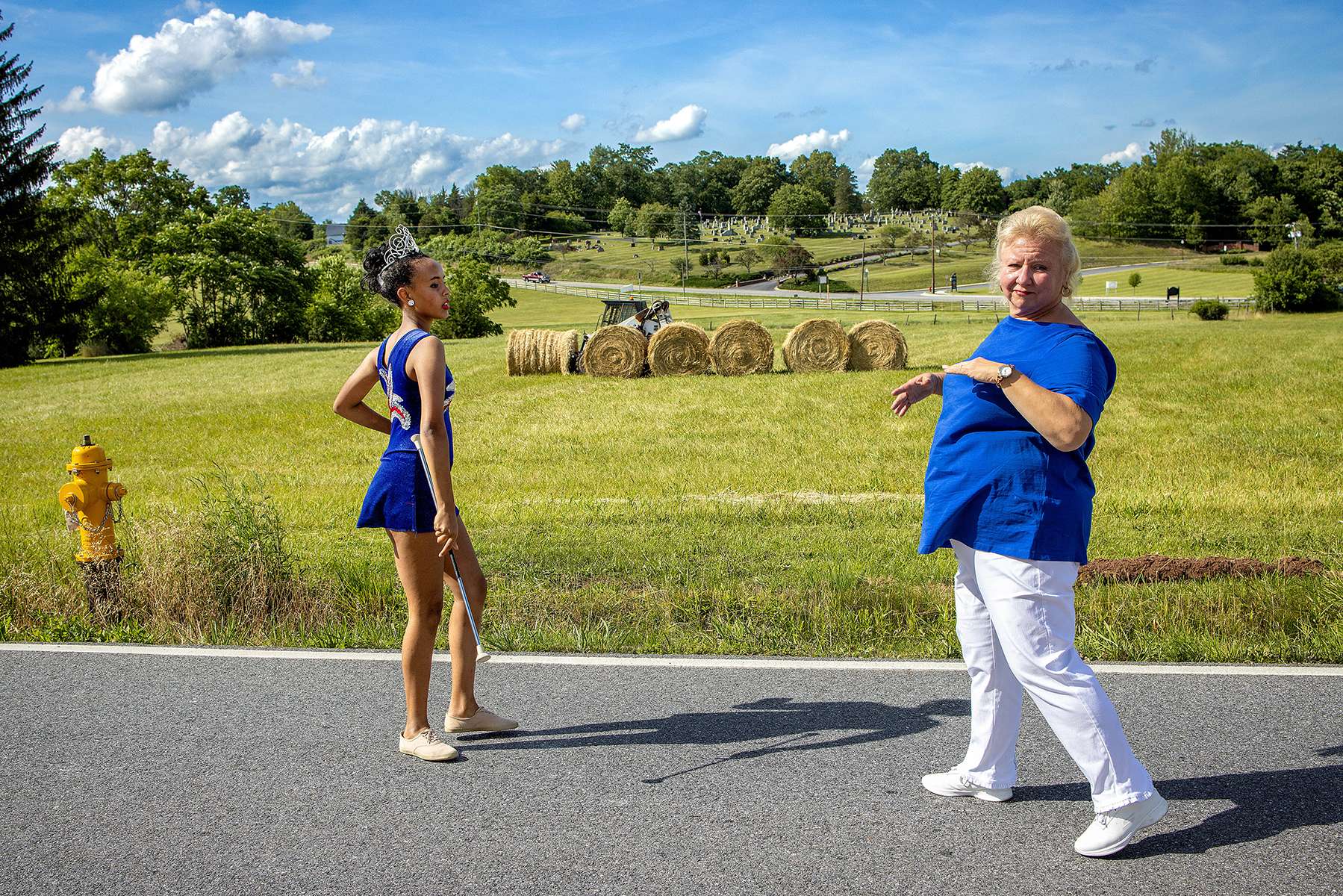 Katie Gaffigan (left) receives coaching from Donna Landsperger before performing with her twirling squad, the Catocin-Aires Twirling and Color Guard Corps, before the start of the Emmitsburg Community Heritage Day Parade in Emmitsburg, Maryland on June 26, 2021. Gaffigan was named and crowned queen of the group for 2021. 