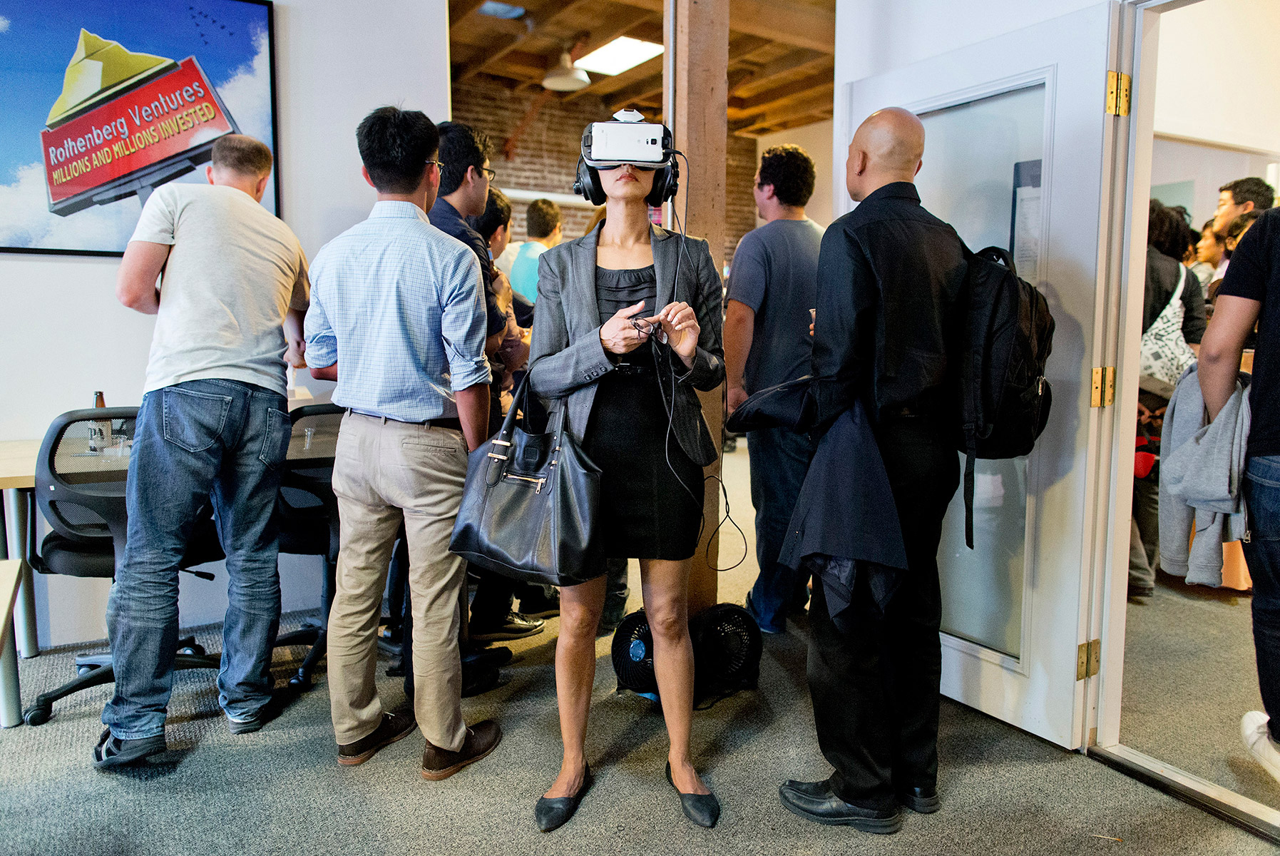 At a happy-hour event at Rothenberg Ventures, a venture capital fund that has investments in various virtual reality, drone and artificial intelligence technologies, an attendee tries on a virtual reality headset as others listen to a speaker in another room at the firm’s office in San Francisco, California in July 2015. Rothenberg, which invests in early-stage technology companies with a focus on millennial founders, started River, a virtual reality accelerator program. 