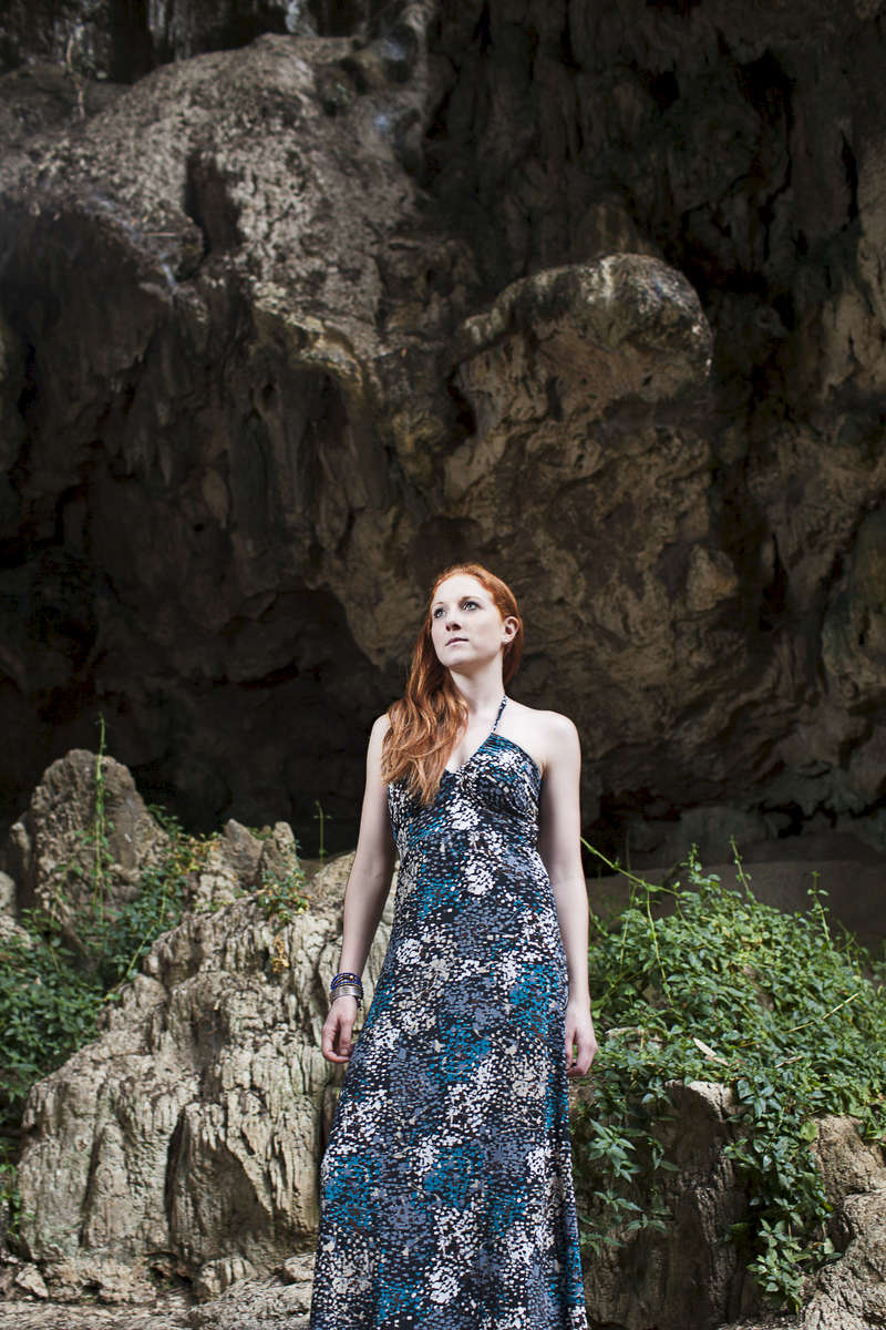 Young woman  stands in a cave in Thailand. by Vermont photographer Judd Lamphere